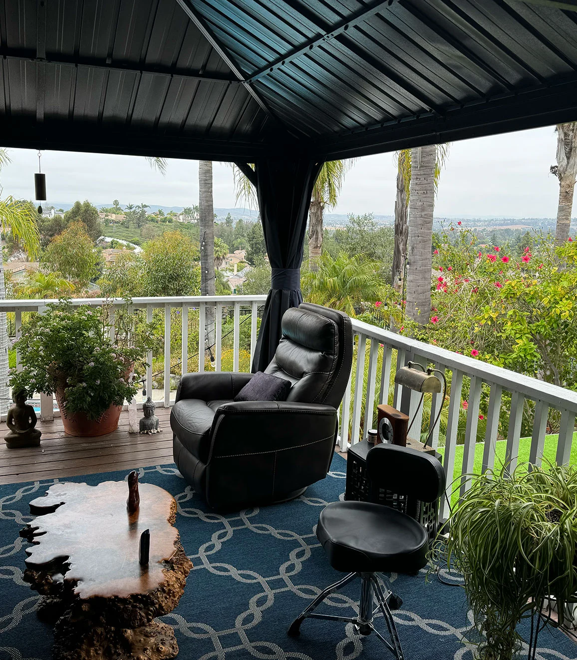 Covered deck retreat space with a leather recliner overlooking a green San Diego County valley